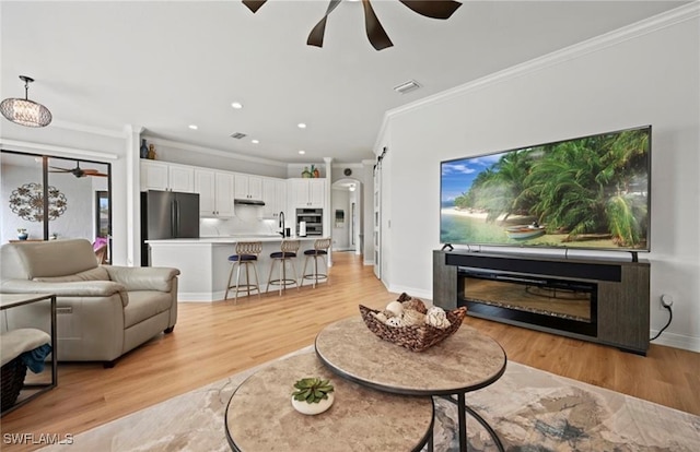 living room featuring light hardwood / wood-style floors, crown molding, and sink