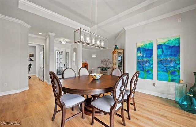 dining space featuring light wood-type flooring, crown molding, and a notable chandelier