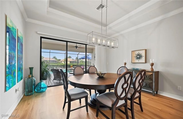 dining space featuring a tray ceiling, hardwood / wood-style floors, and ornamental molding