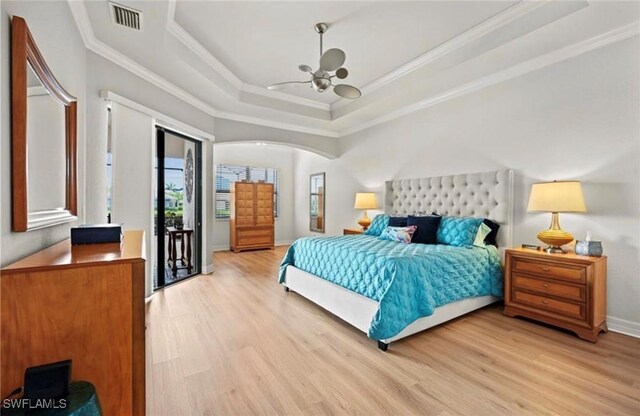 bedroom with a tray ceiling, crown molding, ceiling fan, and light wood-type flooring