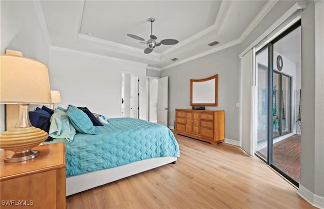 bedroom featuring ceiling fan, access to exterior, light wood-type flooring, and a tray ceiling