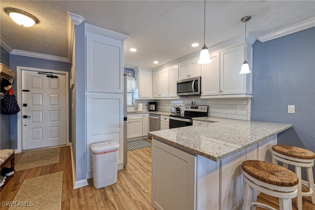 kitchen featuring stainless steel appliances, white cabinetry, hanging light fixtures, and kitchen peninsula