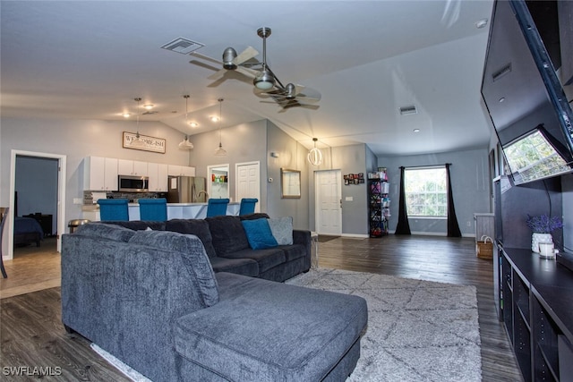 living room with ceiling fan, dark hardwood / wood-style flooring, and vaulted ceiling