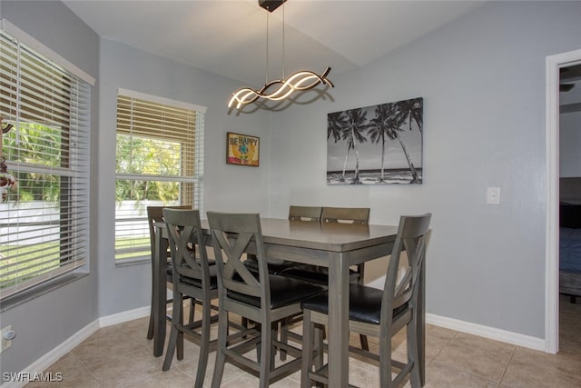 tiled dining room with vaulted ceiling and a notable chandelier