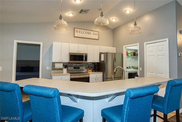 kitchen featuring stainless steel appliances, backsplash, an island with sink, pendant lighting, and white cabinets