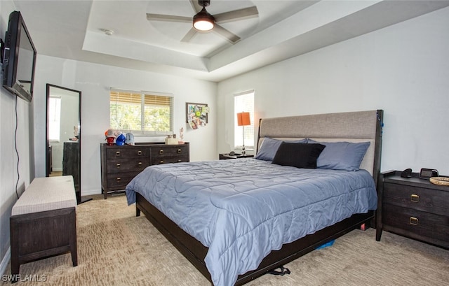 bedroom featuring ceiling fan, light carpet, and a tray ceiling