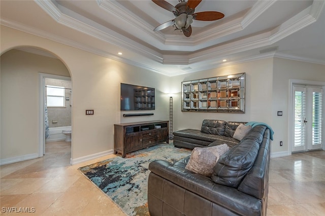 living room featuring ceiling fan, ornamental molding, and a tray ceiling