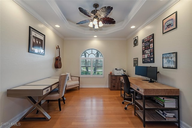 home office featuring light wood-type flooring, a tray ceiling, ceiling fan, and ornamental molding