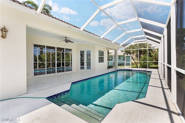 view of pool with glass enclosure, ceiling fan, and a patio