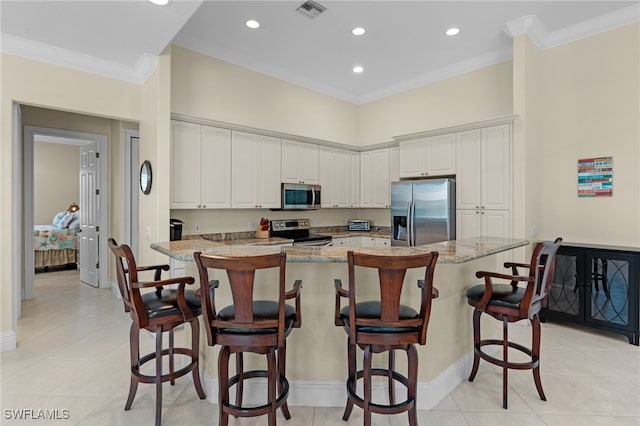 kitchen with a spacious island, light stone countertops, white cabinets, and stainless steel appliances