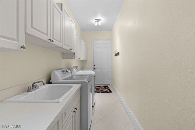 washroom with light tile patterned flooring, cabinets, sink, and washing machine and clothes dryer