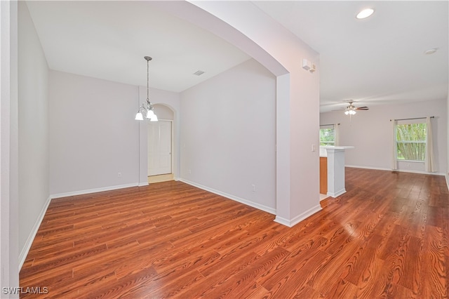 spare room with ceiling fan with notable chandelier and wood-type flooring