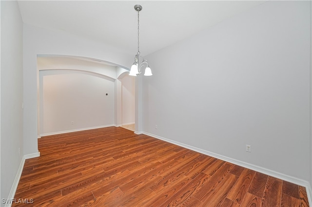 spare room featuring a chandelier and wood-type flooring