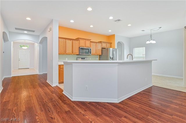 kitchen featuring an island with sink, appliances with stainless steel finishes, and dark wood-type flooring