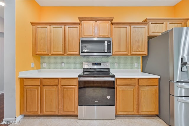 kitchen with appliances with stainless steel finishes, backsplash, and light tile patterned floors