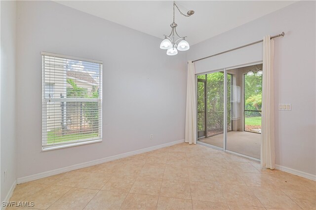 tiled spare room with plenty of natural light and a notable chandelier