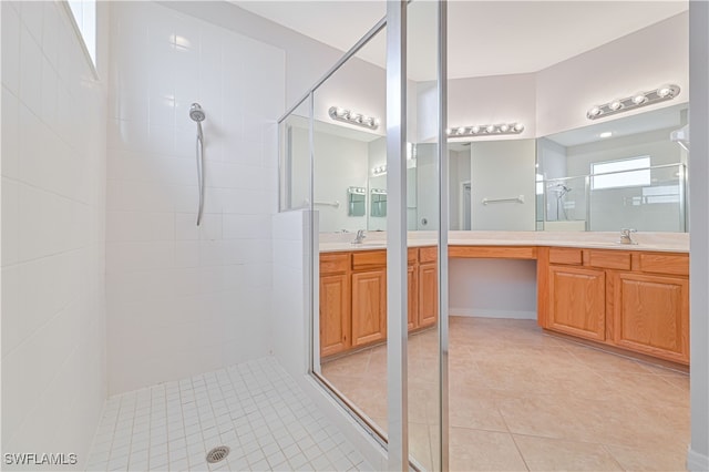 bathroom featuring a tile shower, tile patterned floors, and vanity