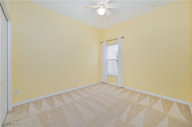 spare room with ceiling fan and light colored carpet