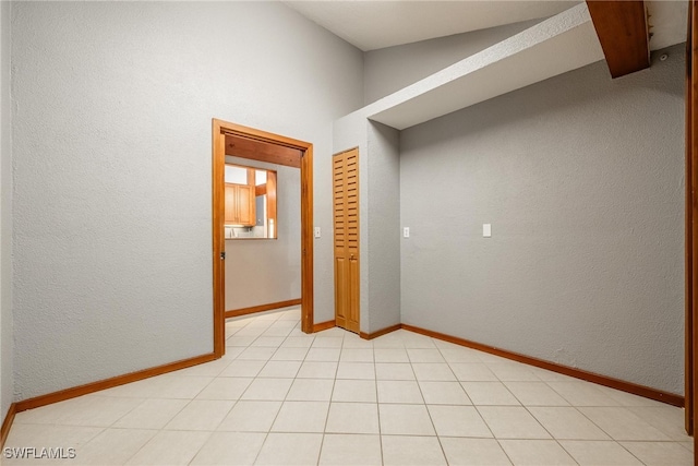 tiled spare room featuring lofted ceiling