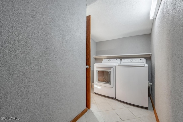 laundry area with washer and dryer, a textured ceiling, and light tile patterned flooring