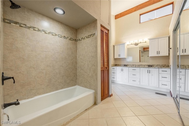 bathroom with tile patterned flooring, vanity, and tiled shower / bath