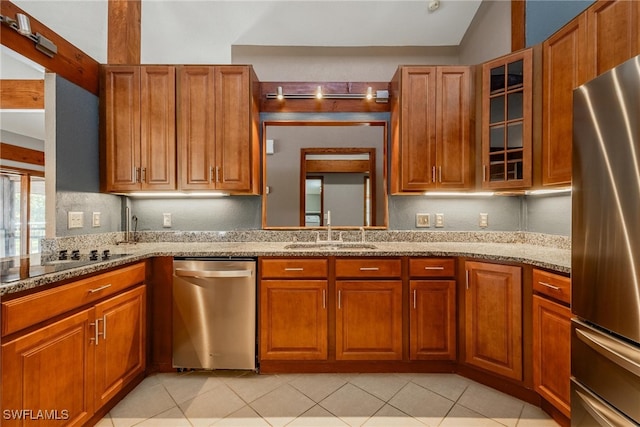 kitchen featuring lofted ceiling, sink, light stone countertops, light tile patterned flooring, and stainless steel appliances