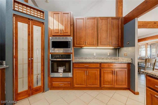 kitchen featuring light stone countertops, light tile patterned floors, and appliances with stainless steel finishes