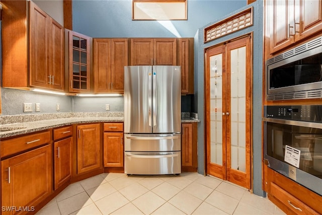 kitchen with light tile patterned floors, stainless steel appliances, and light stone counters