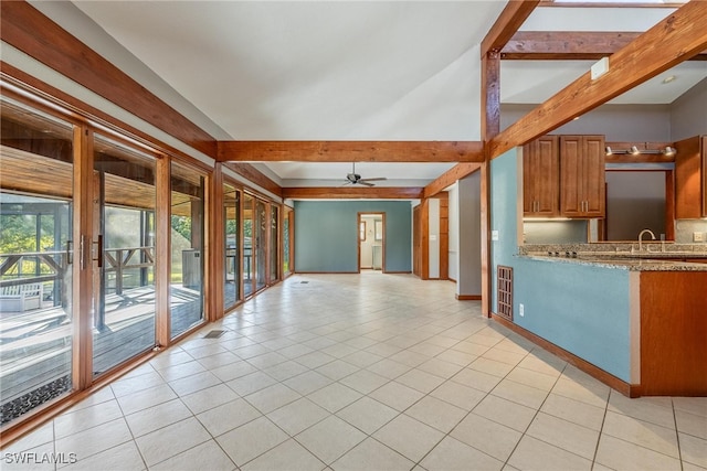 kitchen with beamed ceiling, light tile patterned floors, light stone counters, and ceiling fan