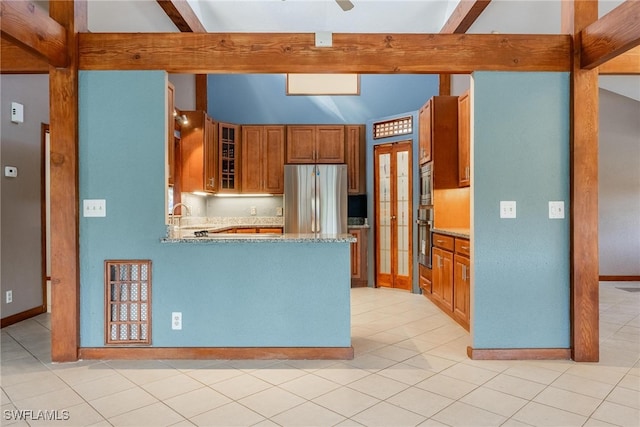 kitchen with beam ceiling, light stone countertops, sink, light tile patterned floors, and appliances with stainless steel finishes