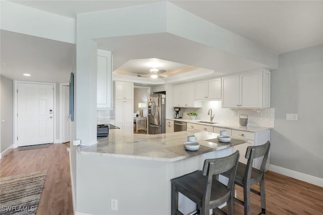 kitchen featuring kitchen peninsula, appliances with stainless steel finishes, white cabinetry, and sink