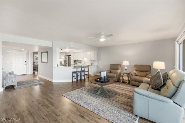 living room featuring hardwood / wood-style floors, ceiling fan, and sink