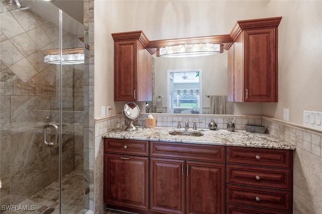 bathroom featuring vanity, an enclosed shower, and tile walls