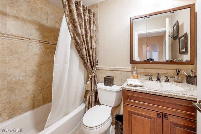 full bathroom with tile walls, vanity, shower / bath combo, and toilet