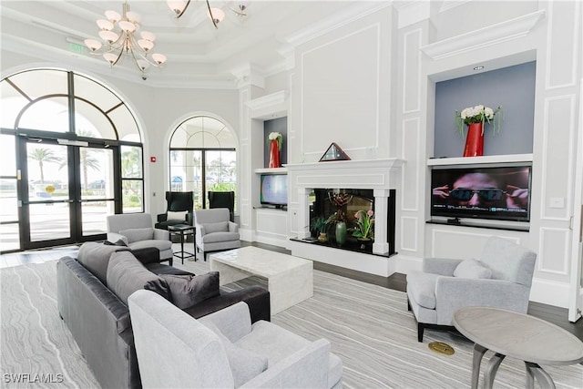 living room featuring a fireplace, french doors, a chandelier, crown molding, and light hardwood / wood-style flooring