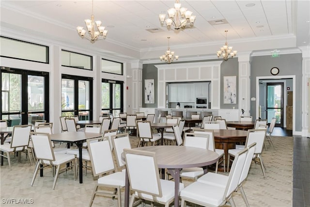 dining area featuring french doors, ornate columns, crown molding, a notable chandelier, and a high ceiling