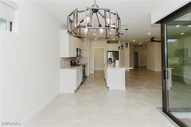 kitchen with stainless steel appliances, tasteful backsplash, hanging light fixtures, and white cabinets