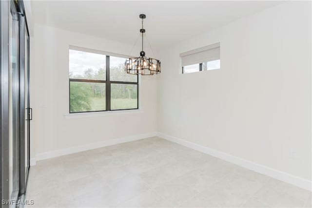 unfurnished room featuring a chandelier