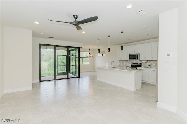 kitchen with appliances with stainless steel finishes, decorative light fixtures, tasteful backsplash, white cabinets, and a center island with sink