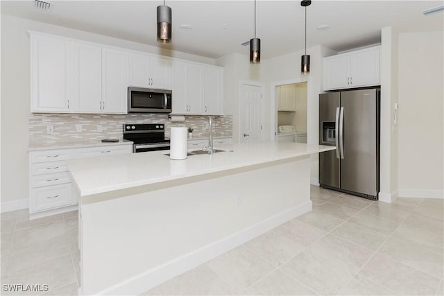 kitchen with appliances with stainless steel finishes, white cabinets, a center island with sink, separate washer and dryer, and decorative light fixtures