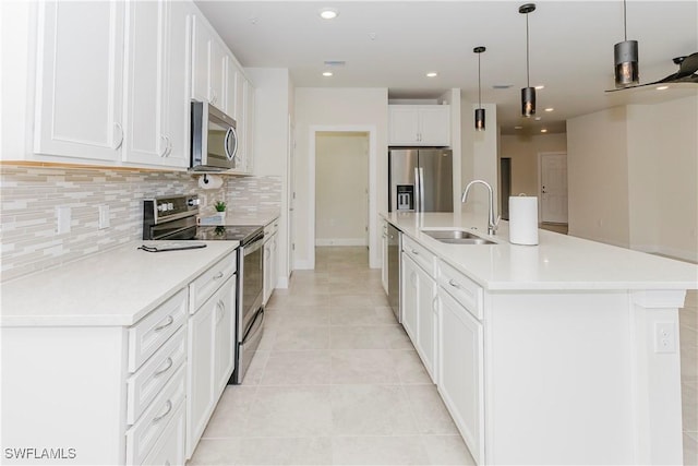 kitchen with pendant lighting, sink, white cabinetry, stainless steel appliances, and a center island with sink