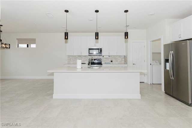 kitchen with stainless steel appliances, decorative light fixtures, and an island with sink