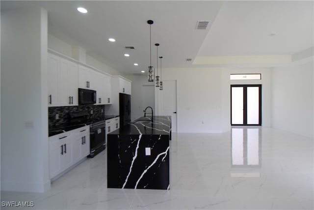 kitchen featuring a kitchen island with sink, black appliances, white cabinets, sink, and hanging light fixtures