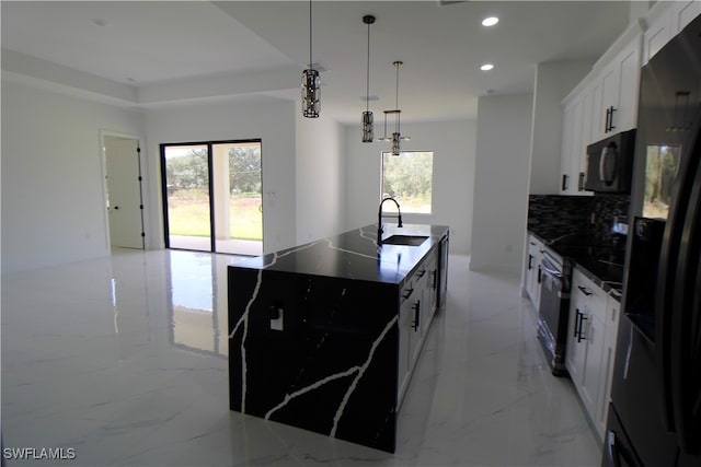 kitchen with white cabinetry, sink, pendant lighting, a center island with sink, and black appliances