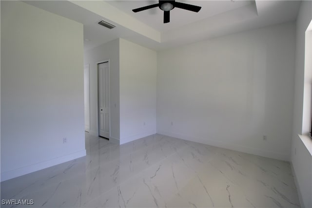 spare room featuring a tray ceiling and ceiling fan