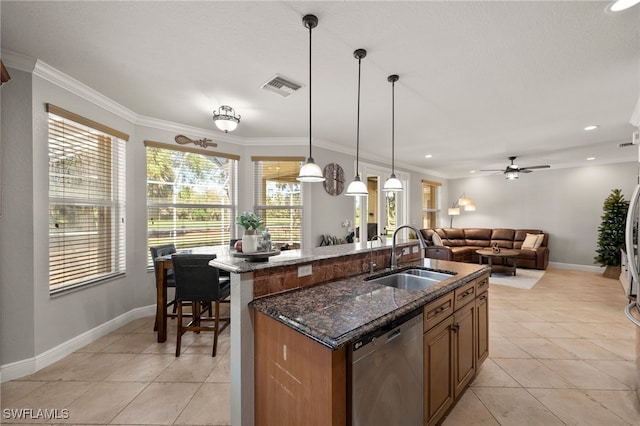 kitchen with stainless steel dishwasher, a kitchen island with sink, sink, dark stone countertops, and hanging light fixtures