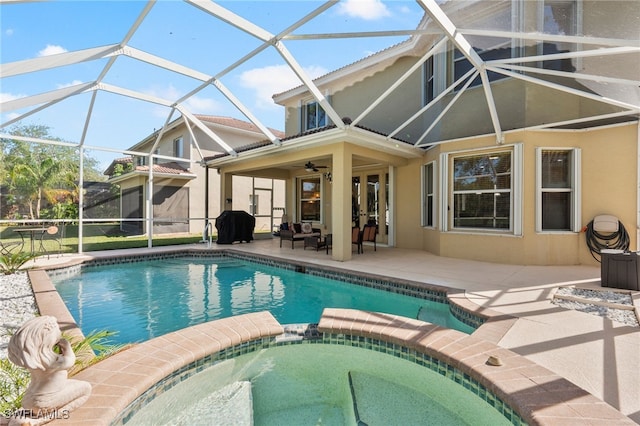 view of pool with glass enclosure, ceiling fan, an in ground hot tub, and a patio