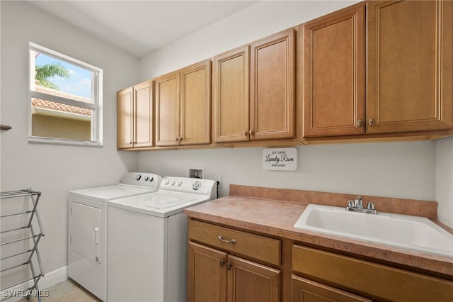 clothes washing area featuring separate washer and dryer, sink, light tile patterned floors, and cabinets