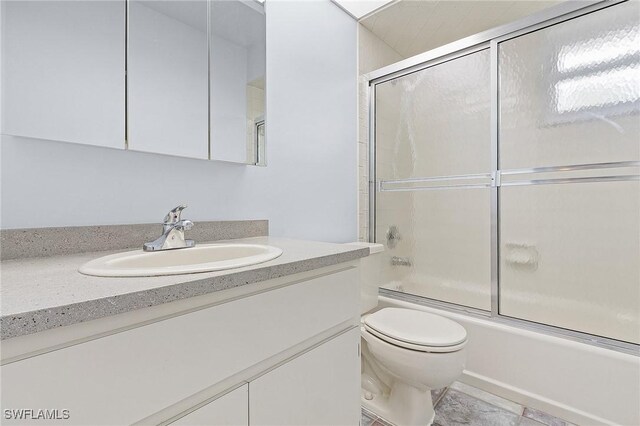 full bathroom with tile patterned floors, vanity, enclosed tub / shower combo, and toilet