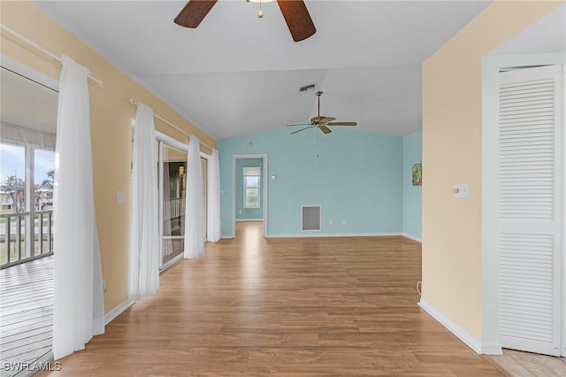 unfurnished living room featuring light wood-type flooring, visible vents, vaulted ceiling, and baseboards